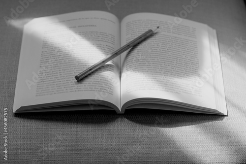 Pencil on an open book and partiallly illuminated by a strip of light photo