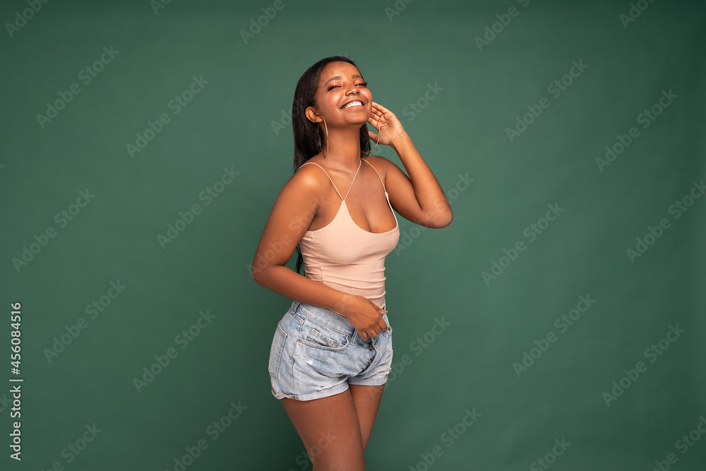 Adorable young African woman looks at camera with joyful expression, big smile.
