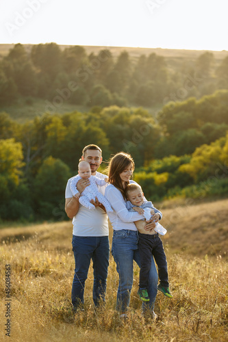 family in light outfits with small children posing against the backdrop of nature