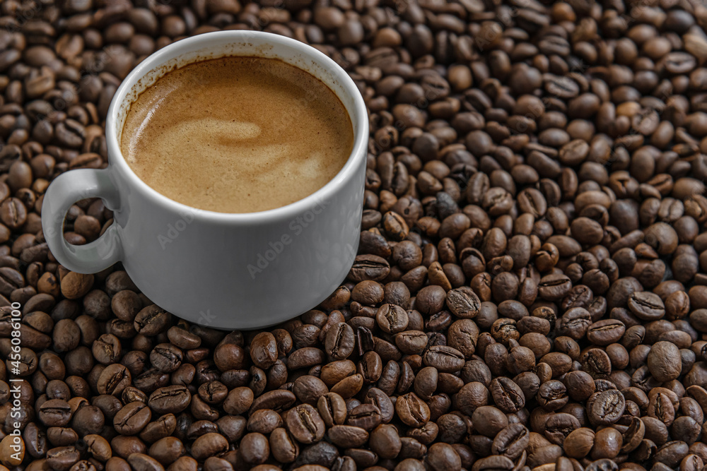 aromatic freshly brewed coffee in a white porcelain cup among coffee beans aromatic freshly brewed coffee in a white porcelain cup among coffee beans