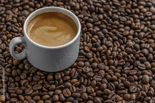 aromatic freshly brewed coffee in a white porcelain cup among coffee beans