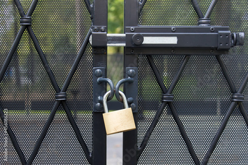 Metallic padlock hanging on fence protection area for no trespassing.