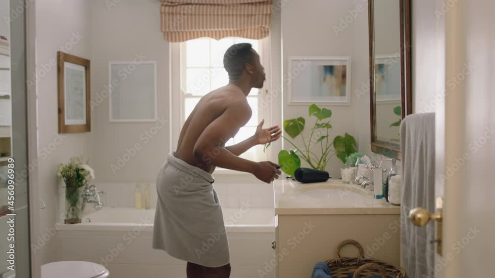 happy african american man dancing shirtless in bathroom looking in mirror having fun morning routine getting ready enjoying positive self image doing silly dance celebrating success happy african american man dancing shirtless in bathroom looking in mirror having fun morning routine getting ready enjoying positive self image doing silly dance celebrating success