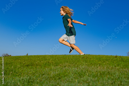 Sweet  happy child boy running playing on a grass in a park at a spring. Active healthy outdoor sport. Fun activity.