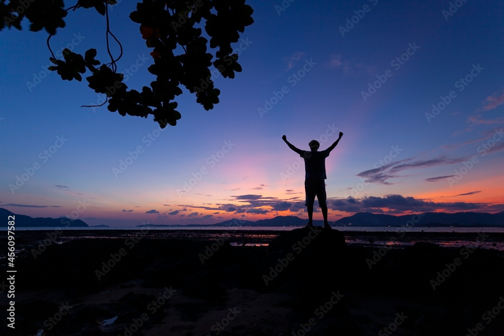 Silhouette of man raised his hands with tree frame at sunset or sunrise sky Silhouette of man raised his hands with tree frame at sunset or sunrise sky