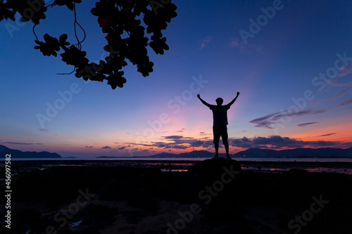 Silhouette of man raised his hands with tree frame at sunset or sunrise sky