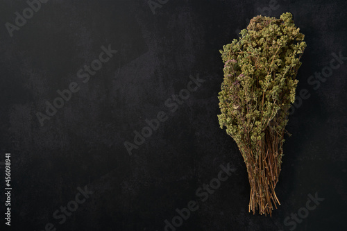 Bunch of oregano on dark background and empty surface.