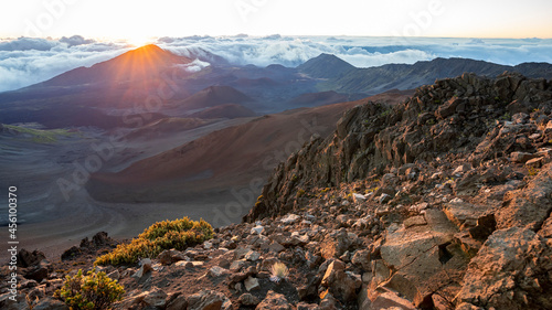 The sun rises dramatically over the dormant volcano and jagged peaks of Haleakala National Park on the island of Maui, Hawaii. 