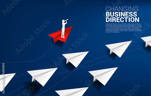 Silhouette of businessman looking through telescope standing on red origami paper airplane is move apart direction from group of white. Business Concept of disruption and niche marketing