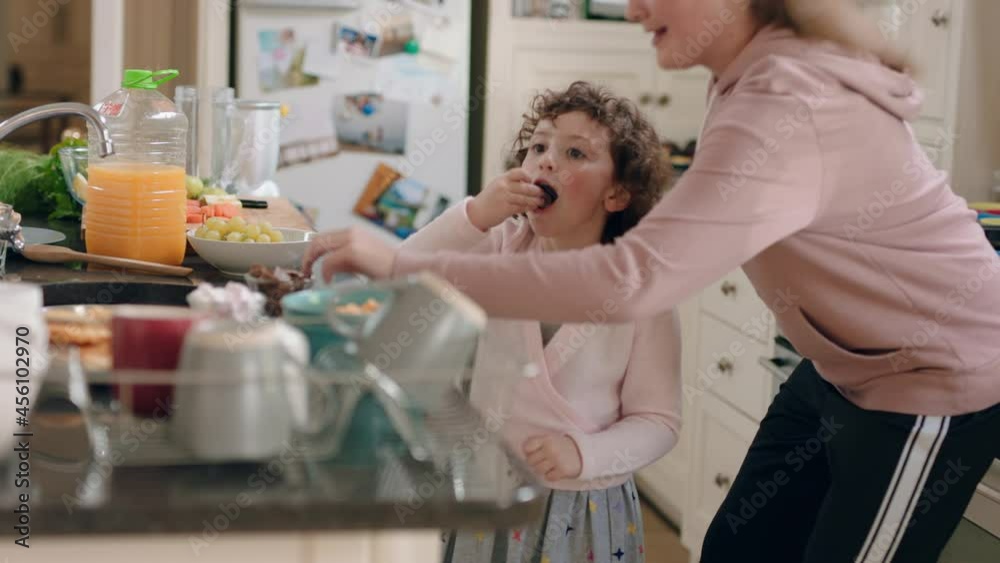 happy teenage girl dancing with little sister in kitchen siblings having fun enjoying funny dance at home together on weekend