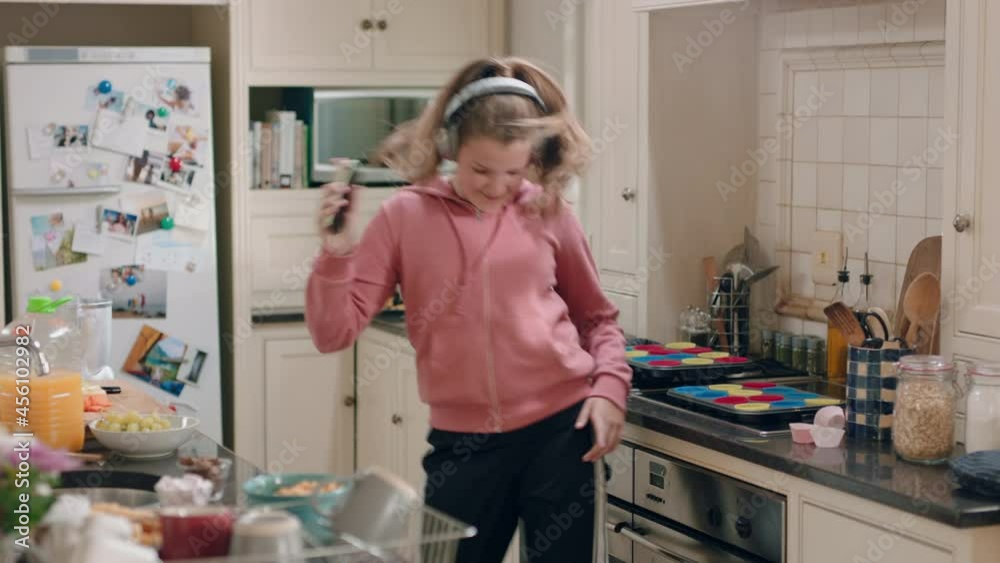happy teenage girl dancing in kitchen having fun celebrating weekend performing funny dance moves listening to music wearing headphones happy teenage girl dancing in kitchen having fun celebrating weekend performing funny dance moves listening to music wearing headphones