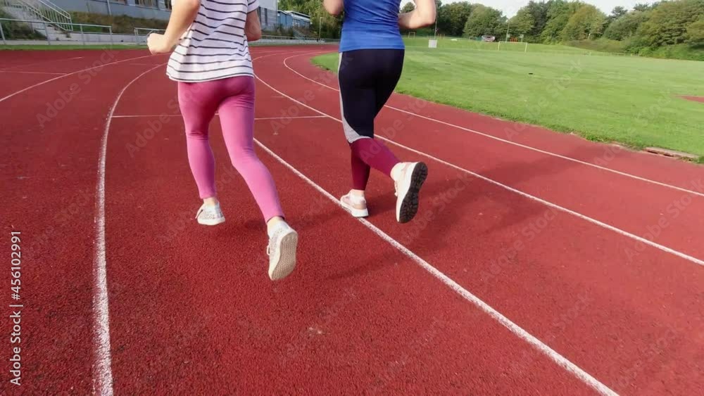 Young woman jogging together with cute fit daughter on stadium at sunset. 60fps 4K video Young woman jogging together with cute fit daughter on stadium at sunset. 60fps 4K video