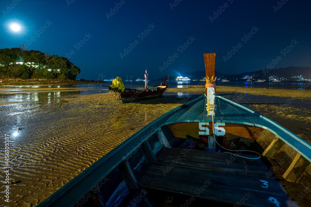 Long exposure night image of long tail wooden boats on the sand of a Thai beach