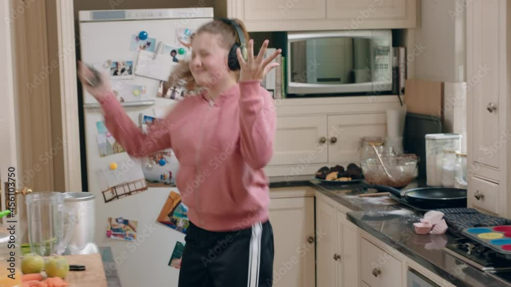 happy teenage girl dancing in kitchen having fun celebrating weekend performing funny dance moves listening to music wearing headphones happy teenage girl dancing in kitchen having fun celebrating weekend performing funny dance moves listening to music wearing headphones