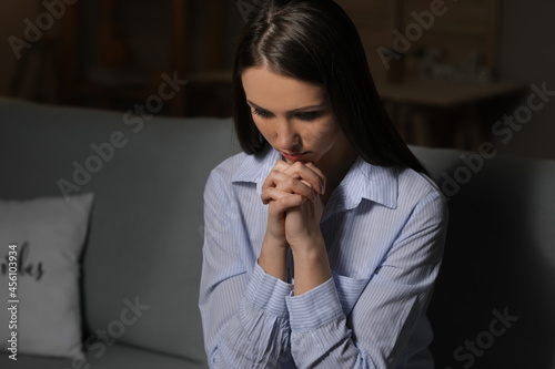 Praying young woman at home...