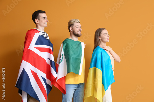 Young people with different flags on color background