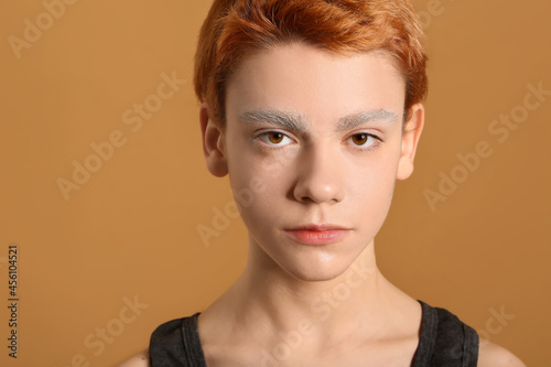 Teenage boy with dyed eyebrows on color background