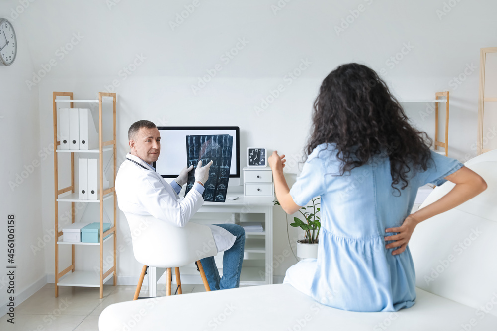 Naklejka premium Mature doctor showing x-ray scan to patient in clinic