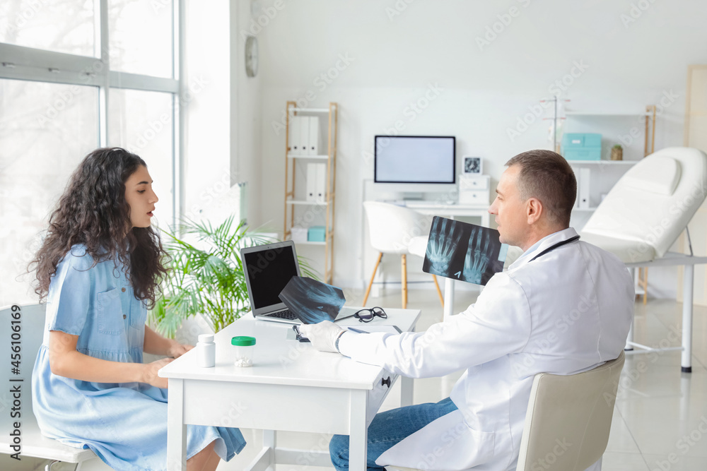 Mature doctor showing x-ray scan to patient in clinic Mature doctor showing x-ray scan to patient in clinic