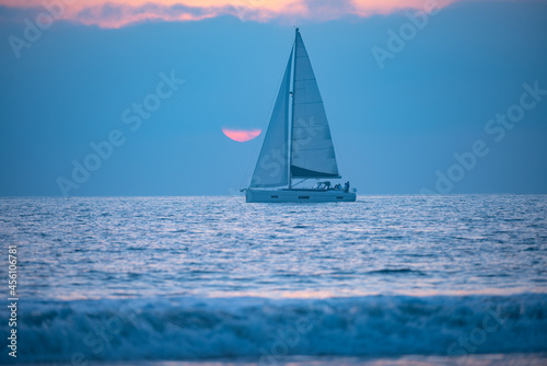 Yacht sailing against sunset. Landscape with skyline sailboat and sunset silhouette. Yachting tourism. Romantic trip on luxury yacht during the sea sunset.
