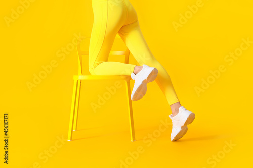 Sporty young woman with chair on color background