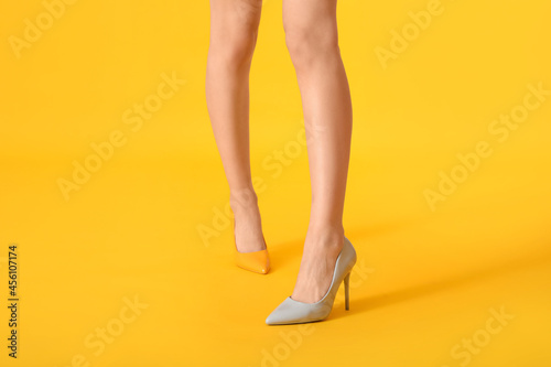 Legs of young woman in different heels on color background