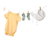 Baby clothes and bib hanging on rope against white background