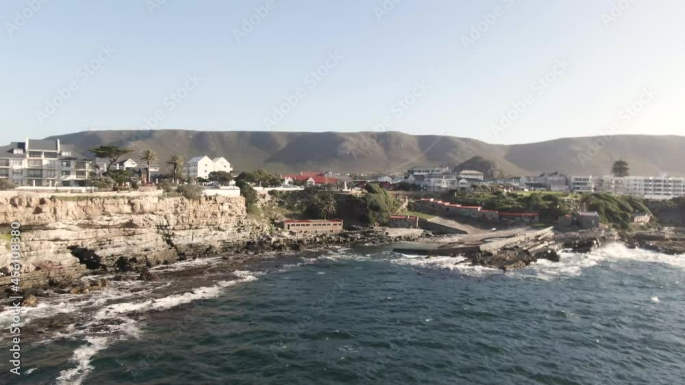 Waves Crashing Through Rocky Shores In An Island With Beautiful Architecture - aerial shot Waves Crashing Through Rocky Shores In An Island With Beautiful Architecture - aerial shot