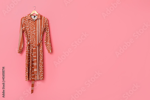 Fotografering Hanger with stylish female dress on color background