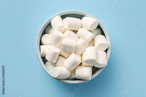 Bowl with tasty marshmallows on color background