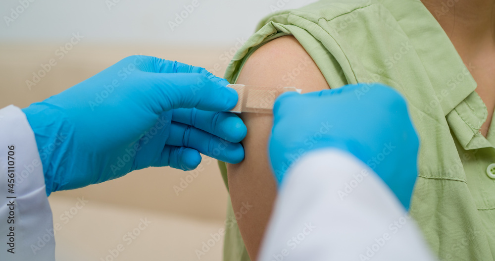 Doctor in blue rubble PPE protective gloves putting adhesive bandage plaster medical on man'arm after injection of COVID'19 CORONA Vaccine. Doctor in blue rubble PPE protective gloves putting adhesive bandage plaster medical on man'arm after injection of COVID'19 CORONA Vaccine.