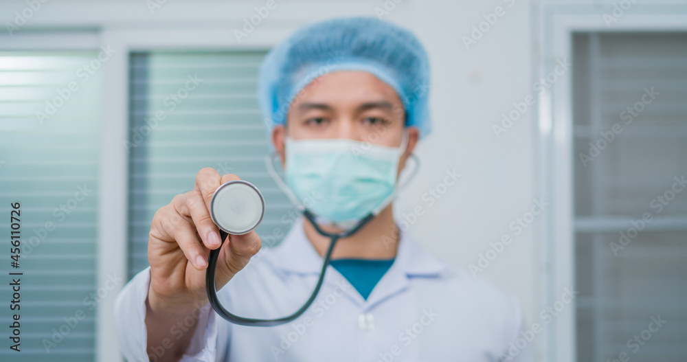 Young and friendly face with smiley eyes Asian doctor wearing surgical hygiene protective mask with copy space stethoscopes to space present something. Advertising concept. Young and friendly face with smiley eyes Asian doctor wearing surgical hygiene protective mask with copy space stethoscopes to space present something. Advertising concept.