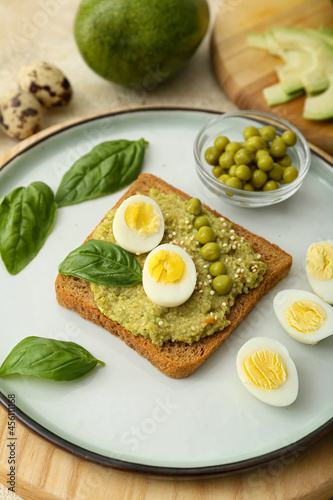 Tasty sandwich with guacamole, eggs and peas on color background, closeup