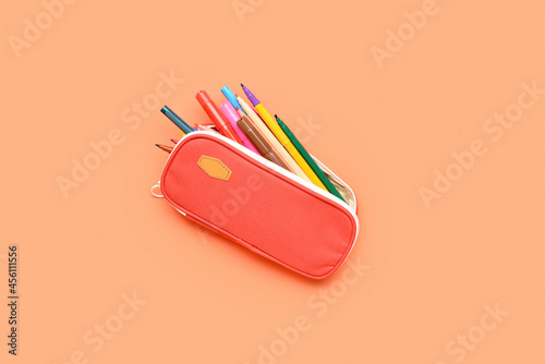 Pencil case with colorful markers on color background