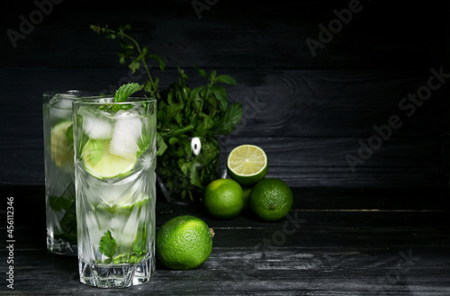 Glasses of fresh mojito, limes and mint on dark wooden background