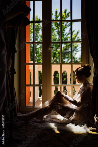 a beautiful and gentle woman in a sexy lace robe sits by the window.