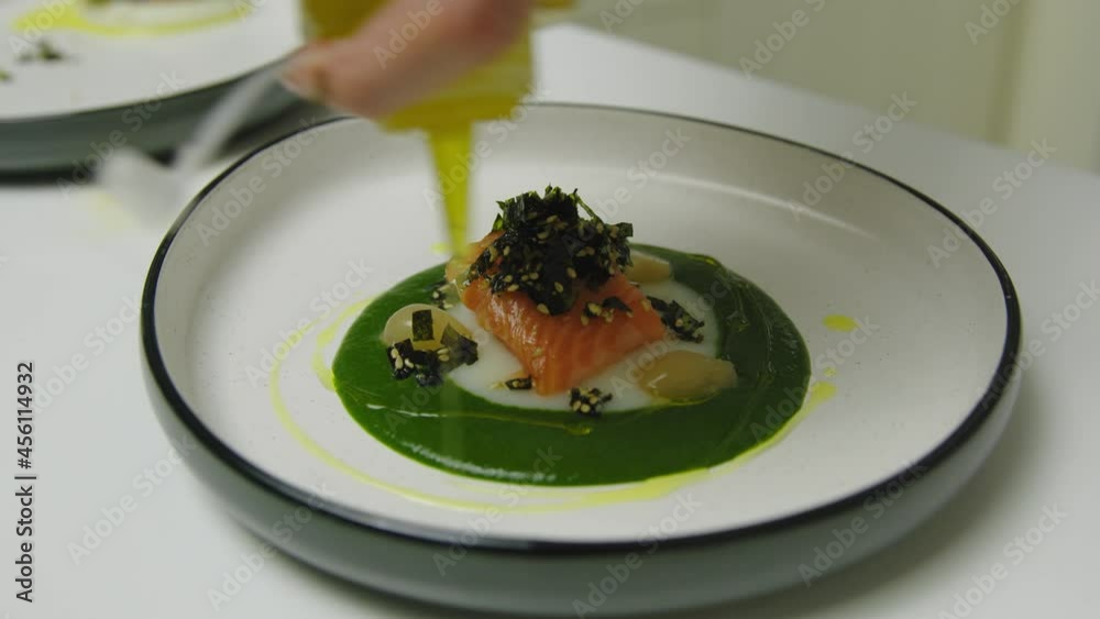 Chef of restaurant serving luxury salmon meal with sauce on plate,close up Chef of restaurant serving luxury salmon meal with sauce on plate,close up