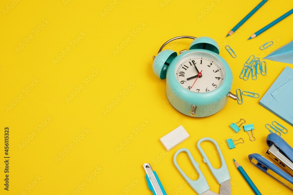 Blue clock with various devices placed on a yellow background. Blue clock with various devices placed on a yellow background.