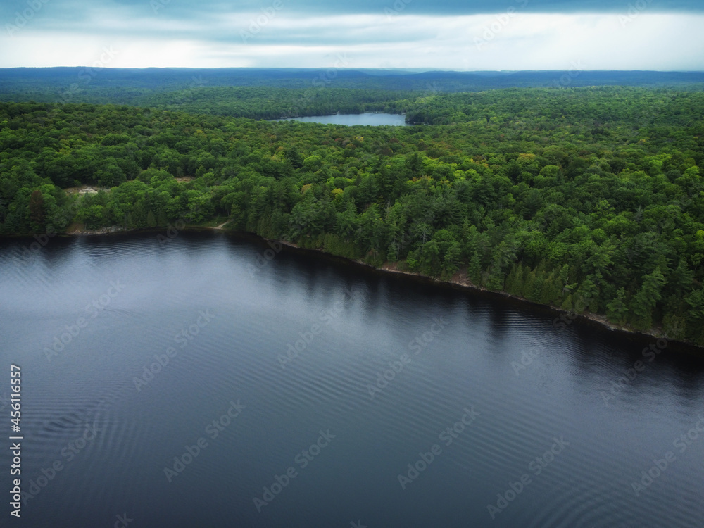 Over Buckskin Lake on an overcast, late summer afternoon with Monrock Lake in the distance. Aerial above crown land wilderness in the Tory Hill area of Highlands East, Ontario, Canada.