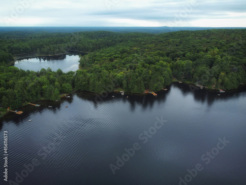 Over Buckskin Lake and Lower Buckskin Lake on a cloudy summer afternoon. Aerial above cottages in the wilderness of crown land located in the Tory Hill, Highlands East, southern Ontario, Canada.