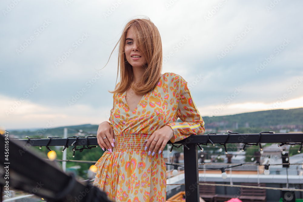 A girl in long dress standing on the stairs on the top of the roof of building. A girl in long dress standing on the stairs on the top of the roof of building.