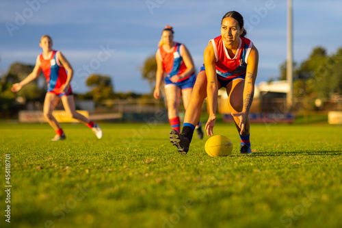 three female footballers in red and blue uniforms playing aussie rules footbal photo