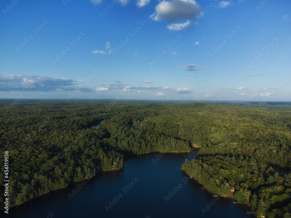 Buckskin Lake on a late summer afternoon. Aerial above the expansive evergreen wilderness of crown land in Tory Hill, Highlands East, Ontario, Canada.