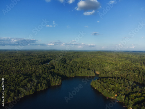 Buckskin Lake on a late summer afternoon. Aerial above the expansive evergreen wilderness of crown land in Tory Hill, Highlands East, Ontario, Canada.