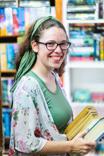 portrait of young woman shopping for second hand books in a store photo