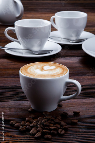 cup of hot cappuccino with pattern on wooden background

