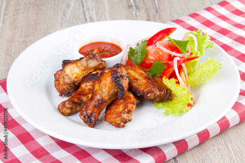grilled chicken wings with tomato spicy sauce and tomatoes with herbs
