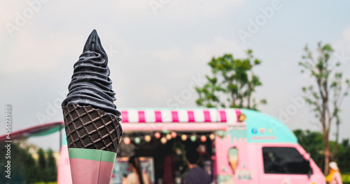 yogurt charcoal or black sesame ice cream on cone with vintage sweet pastel color food truck background, copy space