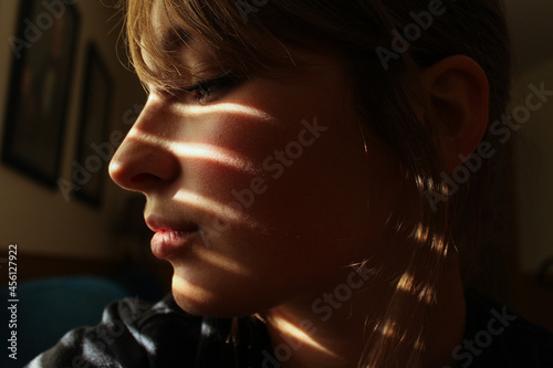 Close up dramatic light and shadows fall on attractive woman's face profile