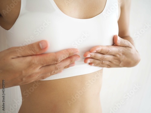 Small breast problem a woman wearing exercise clothes or white underwear. hands holding on chest. Breast augmentation concept. closeup photo, blurred.
